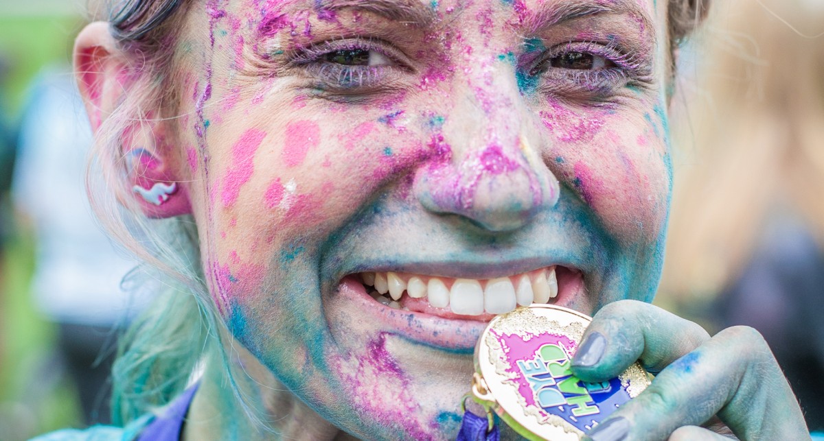 female covered in colored powder with medal